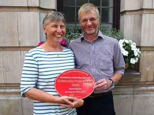Two people holding a Community Project Award