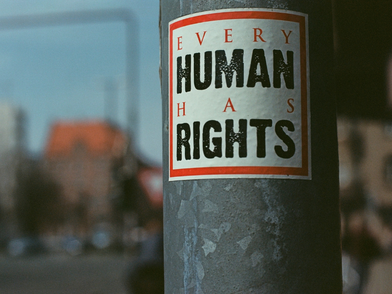 A lampost with a white sticker with a red border, inside of which says "Every human has rights".