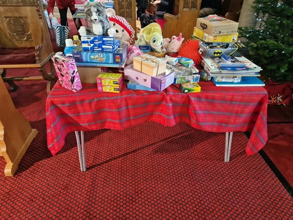 Christmas gifts lay on a table to be given to charity.