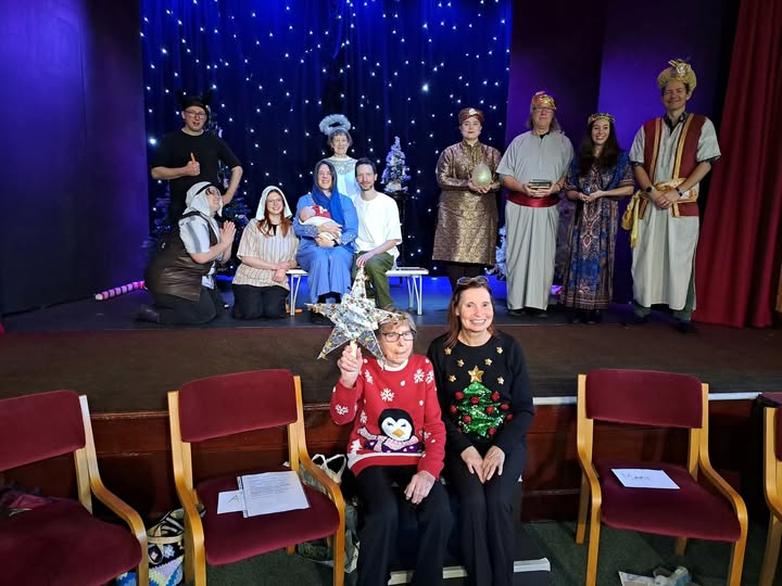 A dramatic group standing on the altar of a church, dressed in nativity costumes.